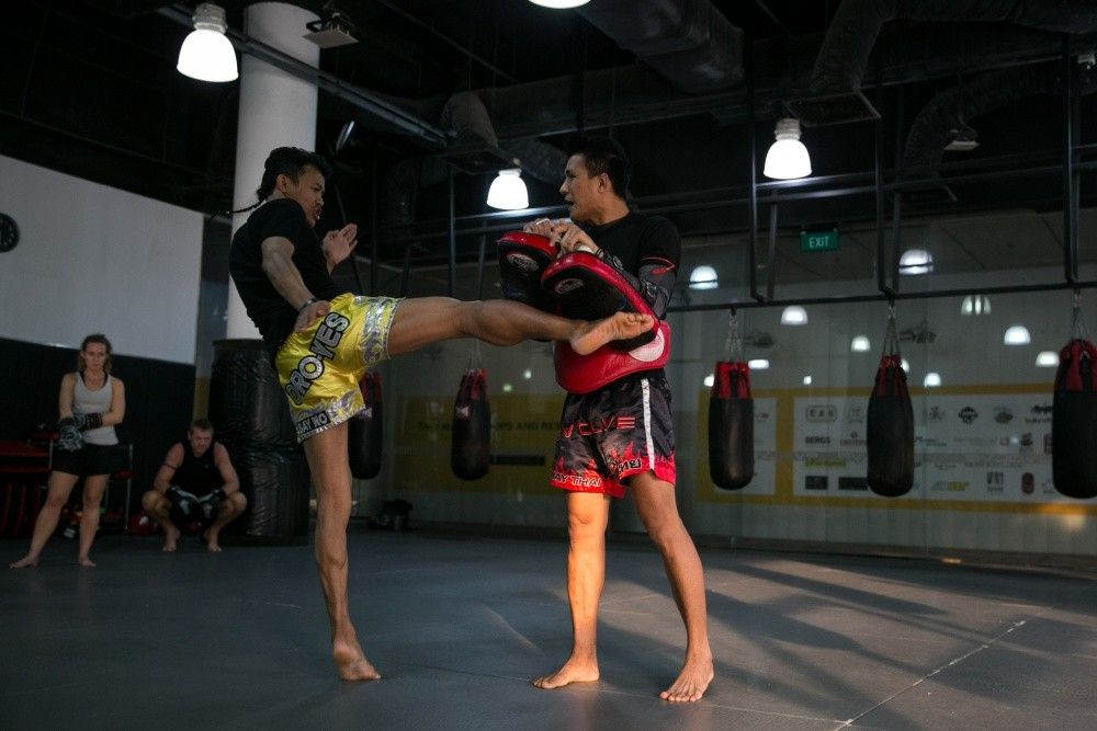Multiple-time Muay Thai World Champion Orono Wor Petchpun demonstrates a right kick with multiple-time Lumpinee Muay Thai World Champion Namsaknoi Yudthagarngamtorn. 
