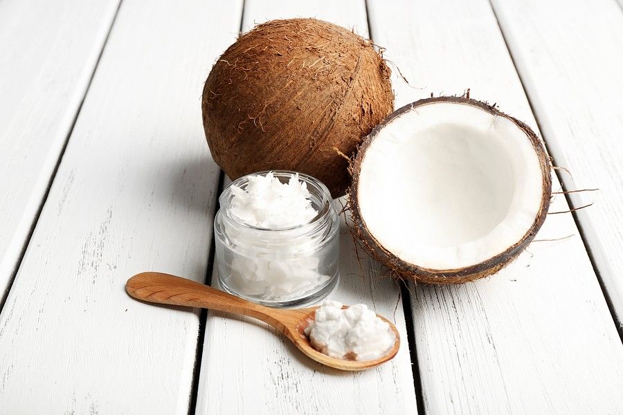 Coconut with coconut oil in jar on wooden background